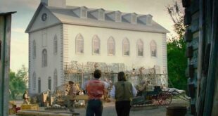 Two men observe a building under construction.