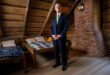 Man in suit standing in rustic attic interior.