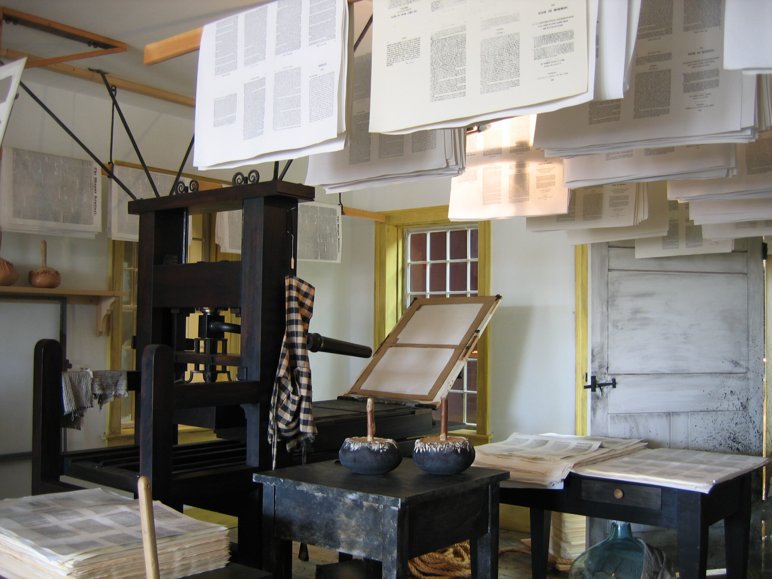 A handpress and suspended printed sheets in the restored Grandin print shop